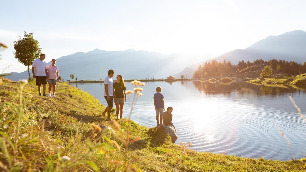 Personen wandern am Ufer eines Bergsees
