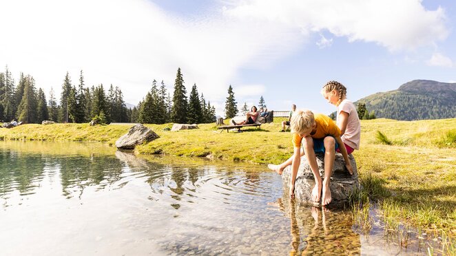 Person am Ufer des Högsees mit Bergpanorama