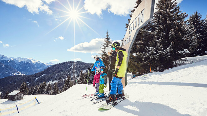 Familie mit Skiausrüstung auf der verschneiten Piste