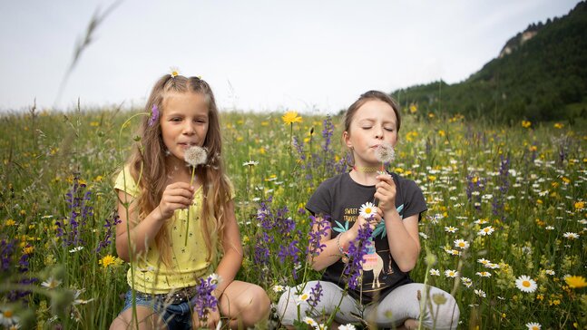 Zwei Kinder sitzen in einer blühenden Blumenwiese