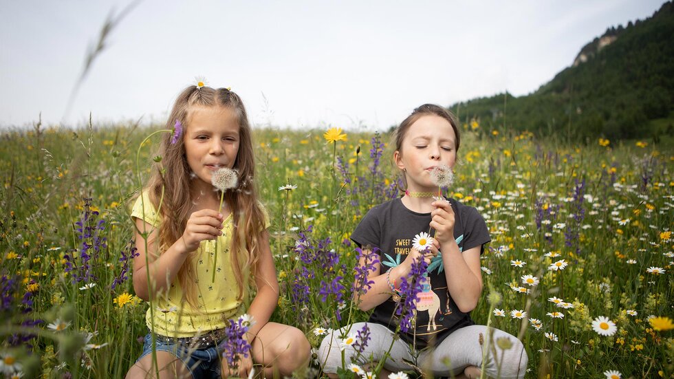 Zwei Kinder sitzen in einer blühenden Blumenwiese